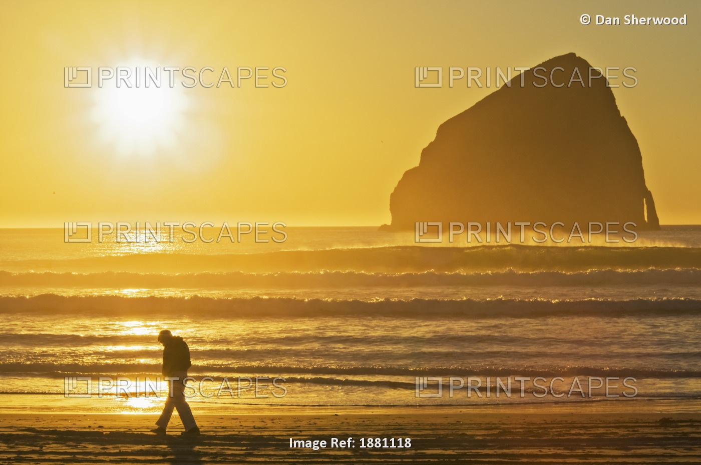 A Person Walking On The Beach At Sunset With Haystack Rock In The Background; ...